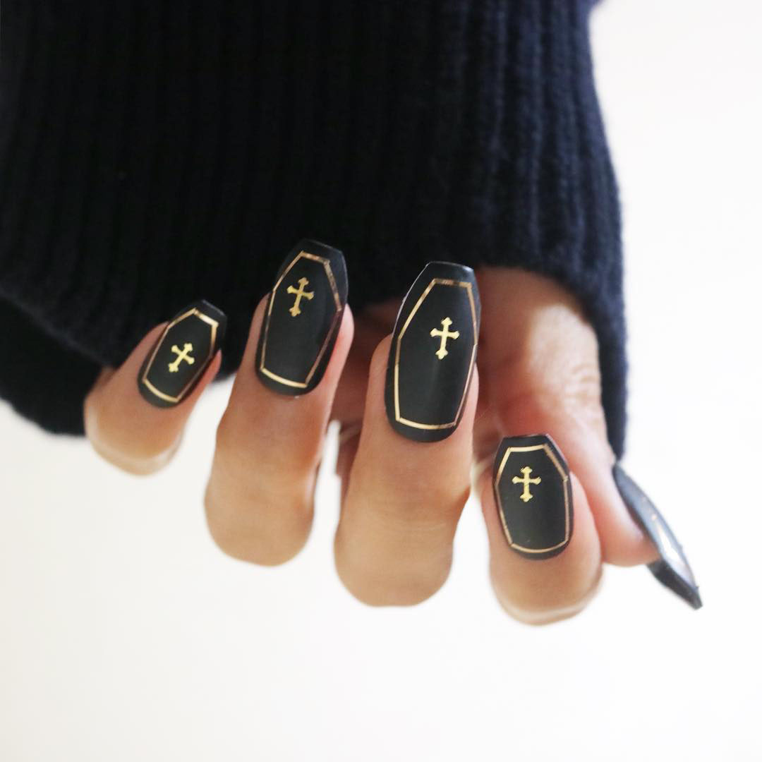 Shaped nails painted black with gold accents to look like a coffin.