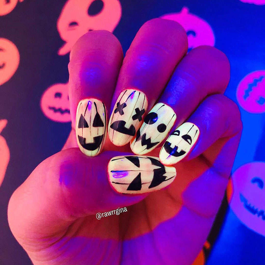 Glow-in-the-dark nails with different jack-o'-lantern faces.