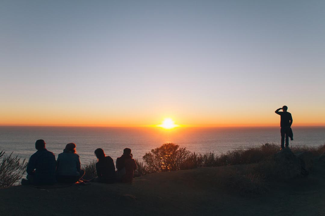 Group of people having a picnic and watching the sunrise.