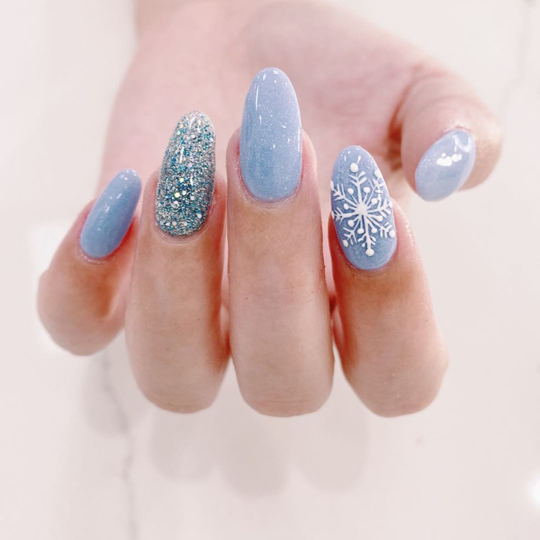 Nails with blue glitter on snowflakes.