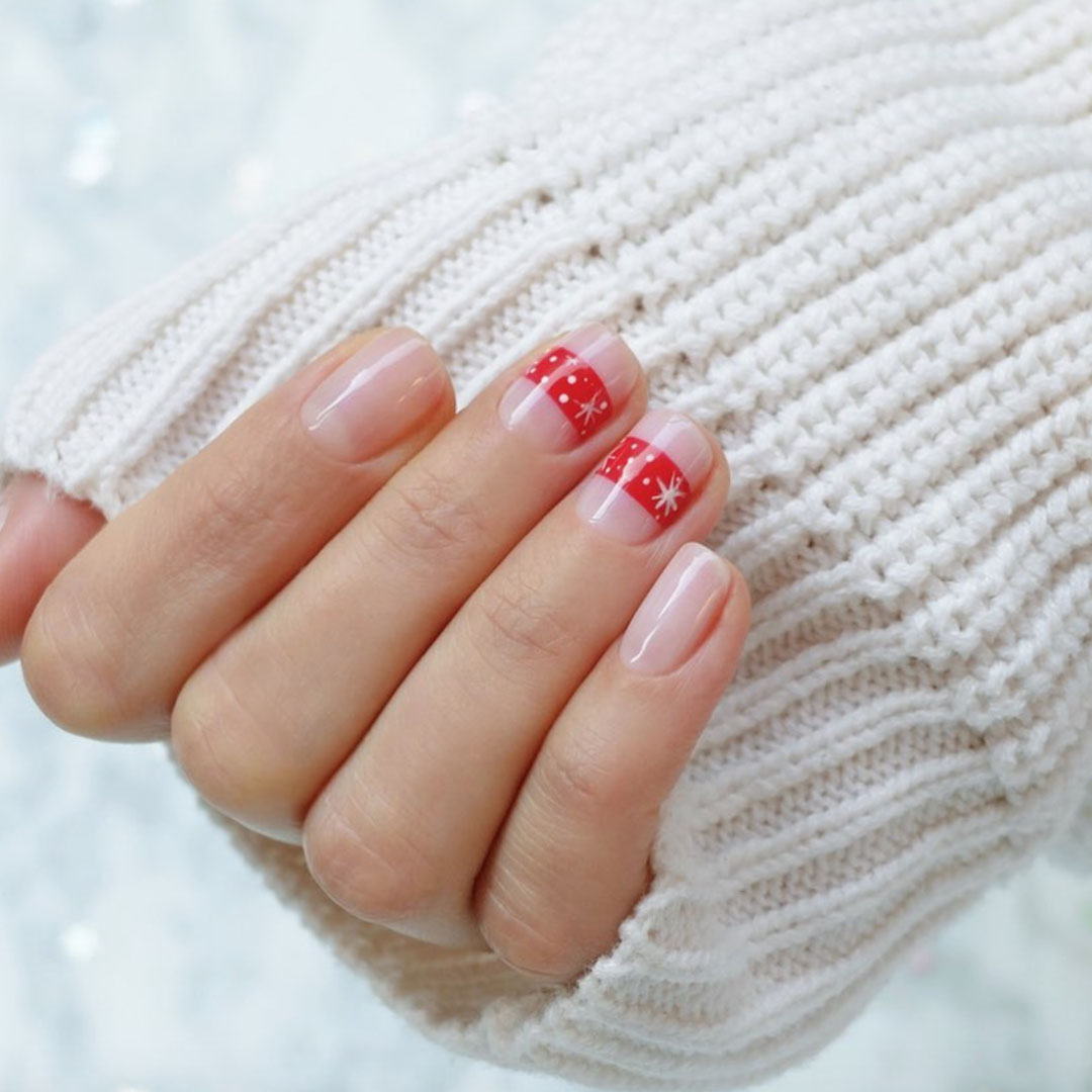 Nails with a simple red strip with snowflakes.